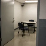Empty police interview room with an open door and two chairs