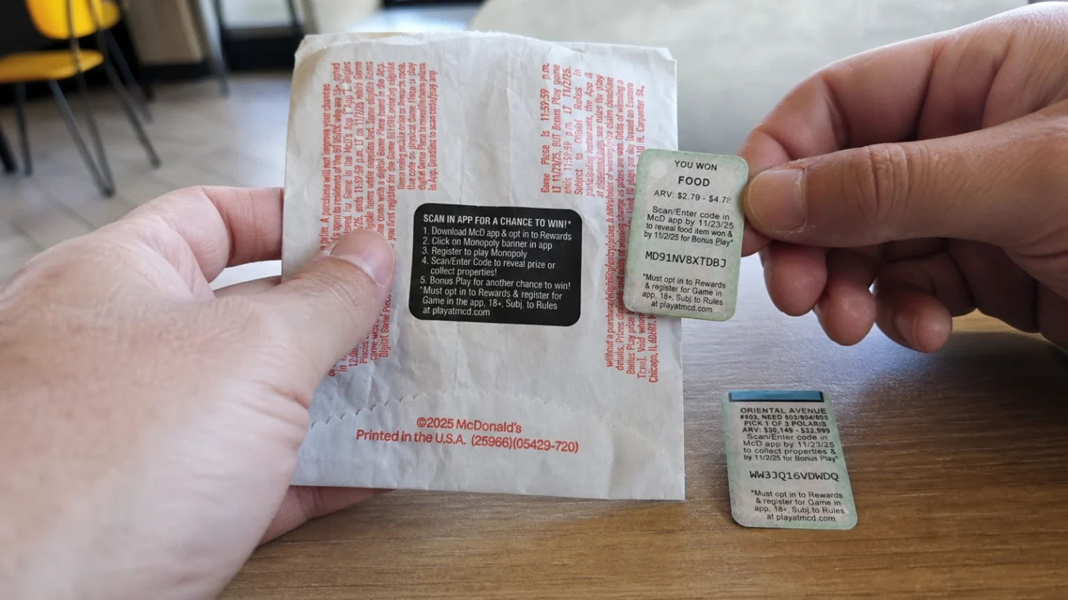 A hand peels a blank game tab from an unbranded takeout carton on a restaurant table.