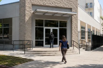 Two visitors approaching a public-service office entrance with steps and an access ramp.