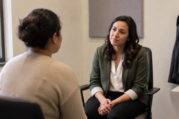 Two adults having a seated intake conversation in a modest community-service office.
